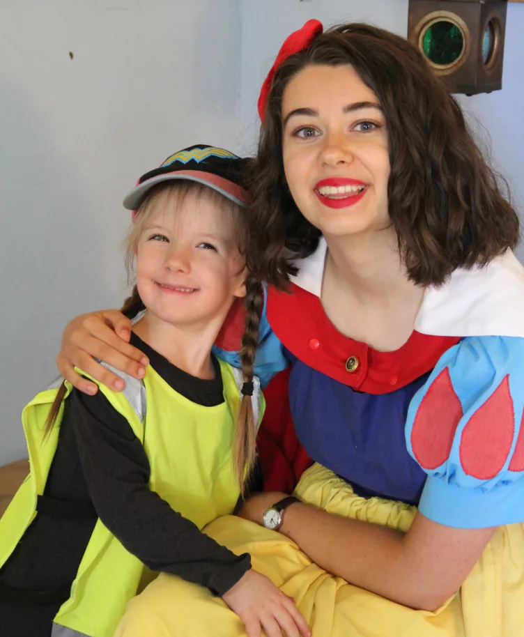 Enfant souriant dans les bras du personnage de Blanche-Neige