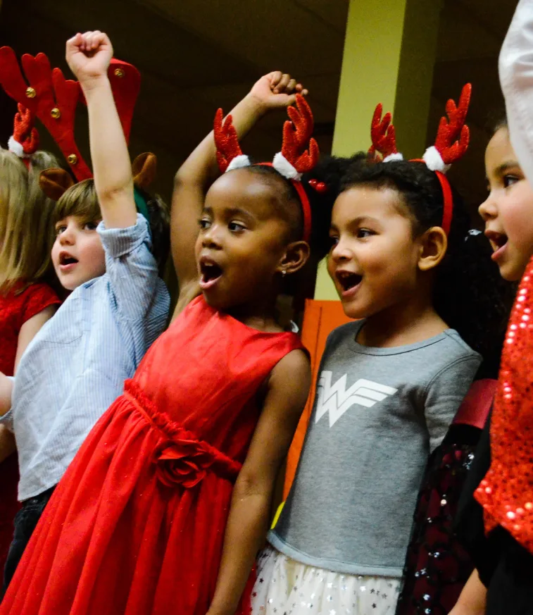 Des enfants avec des serre-têtes de bois de renne chantent en levant le poing