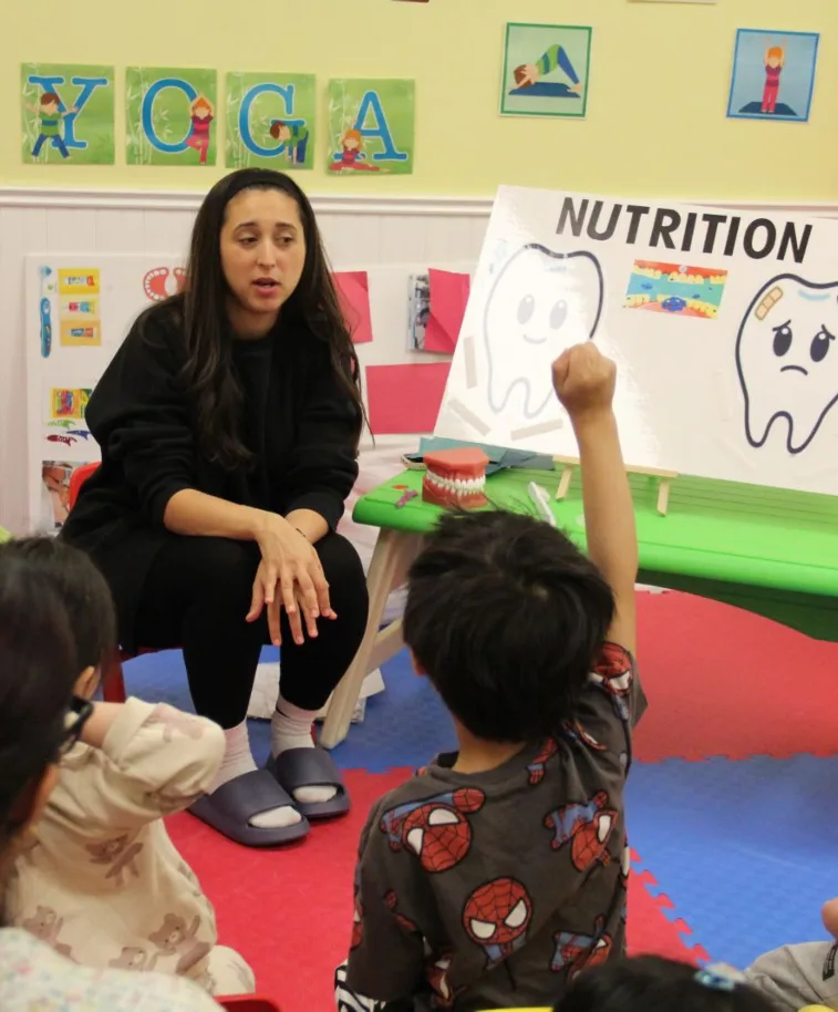 L'hygiéniste présente une affiche sur la nutrition avec des dents pendant qu'un enfant lève la main