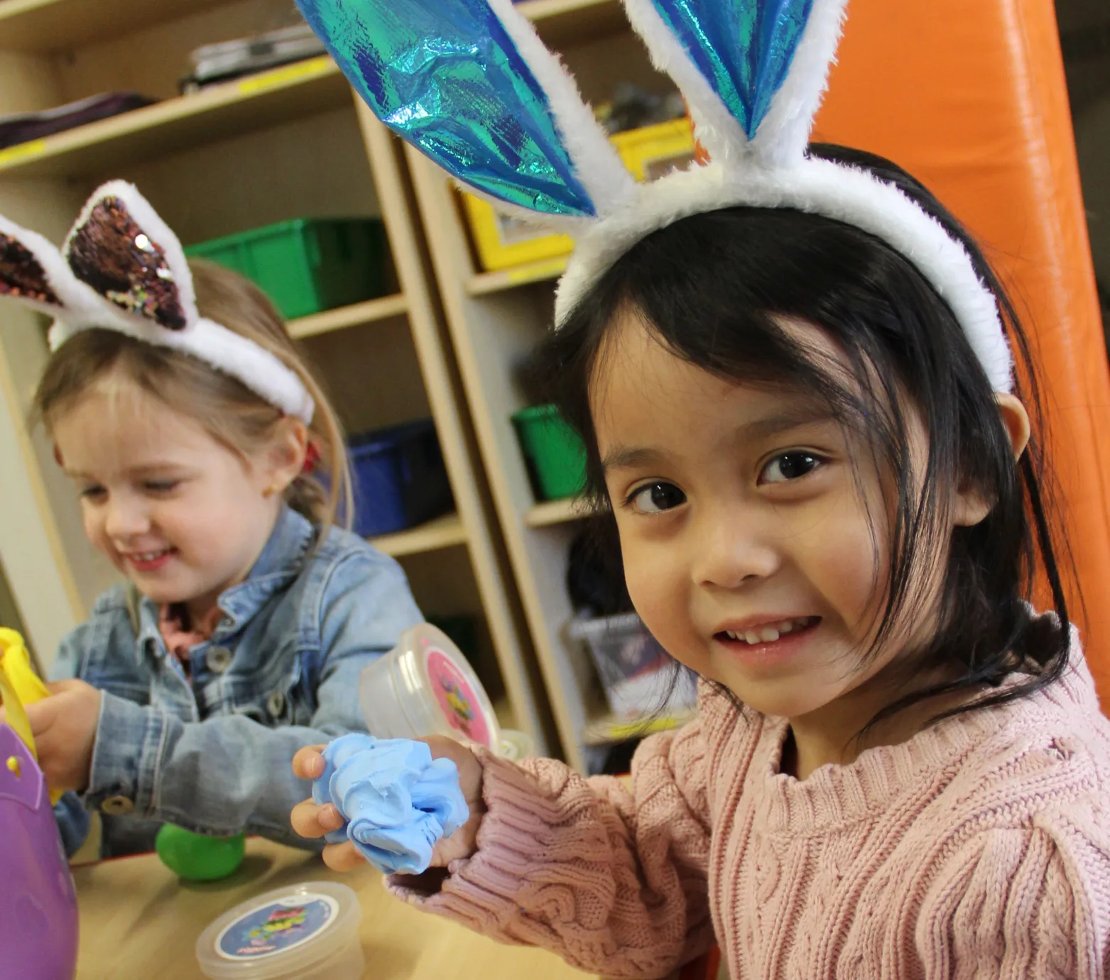 Deux fillettes souriantes portant des oreilles de lapin pendant un bricolage de Pâques