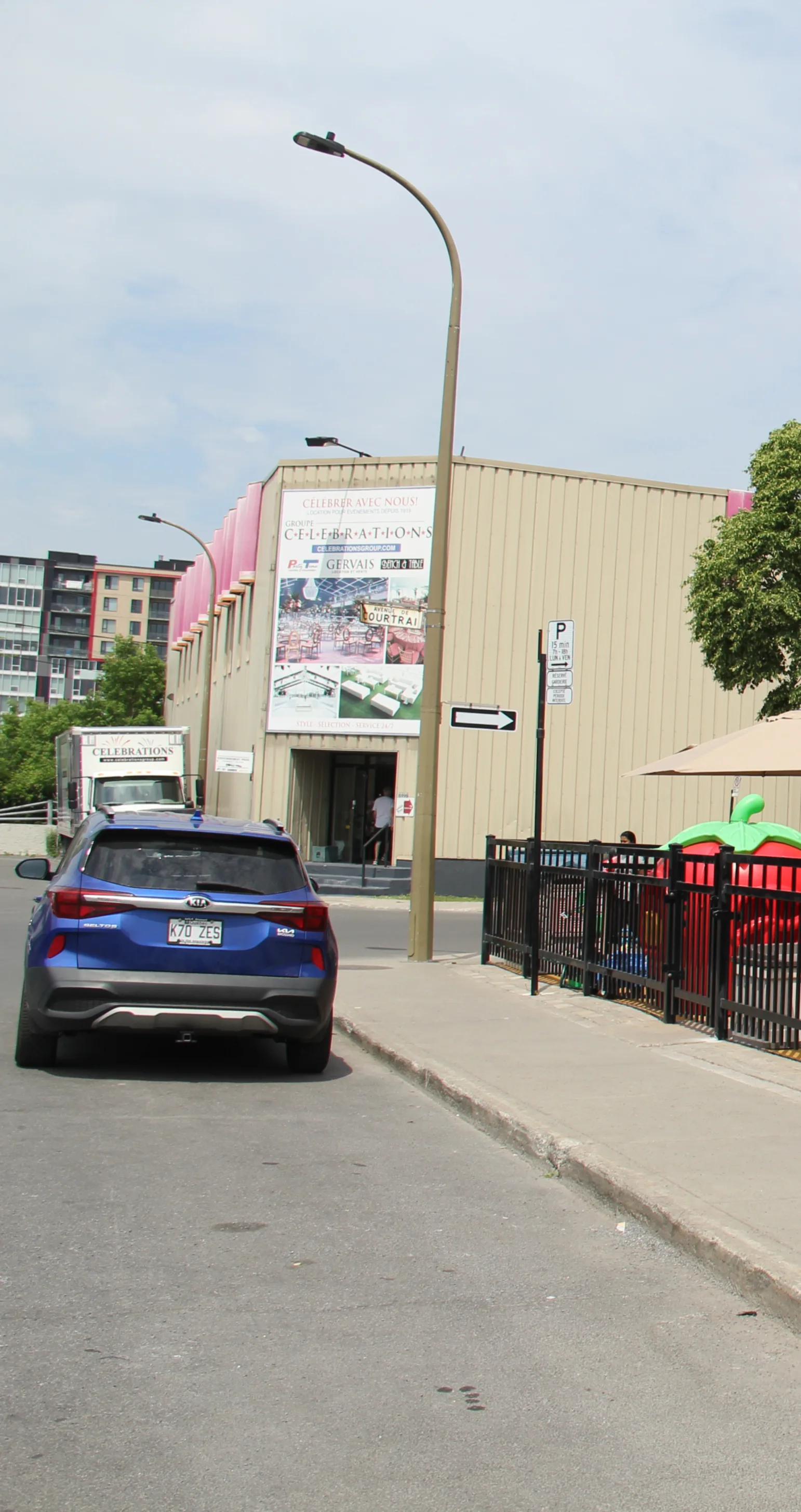 VUS bleu stationné sous un panneau de stationnement, à côté de la garderie et de la cour clôturée