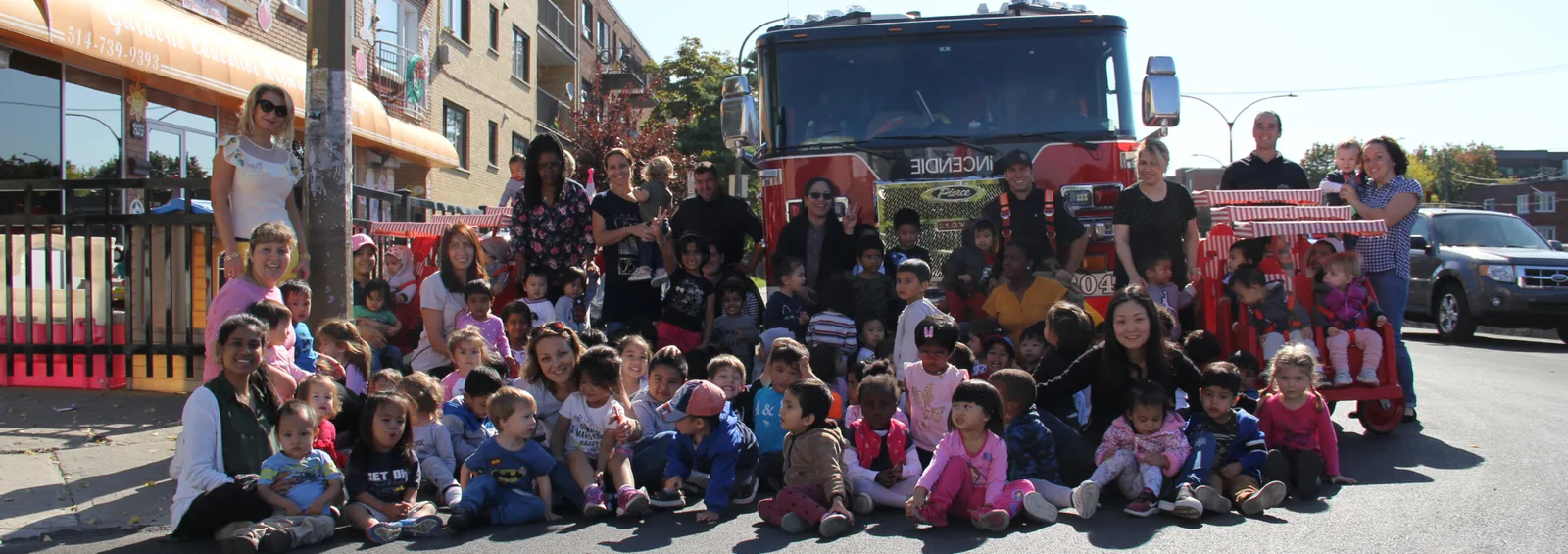 Enfants et éducatrices rassemblés devant un camion de pompiers par une journée ensoleillée