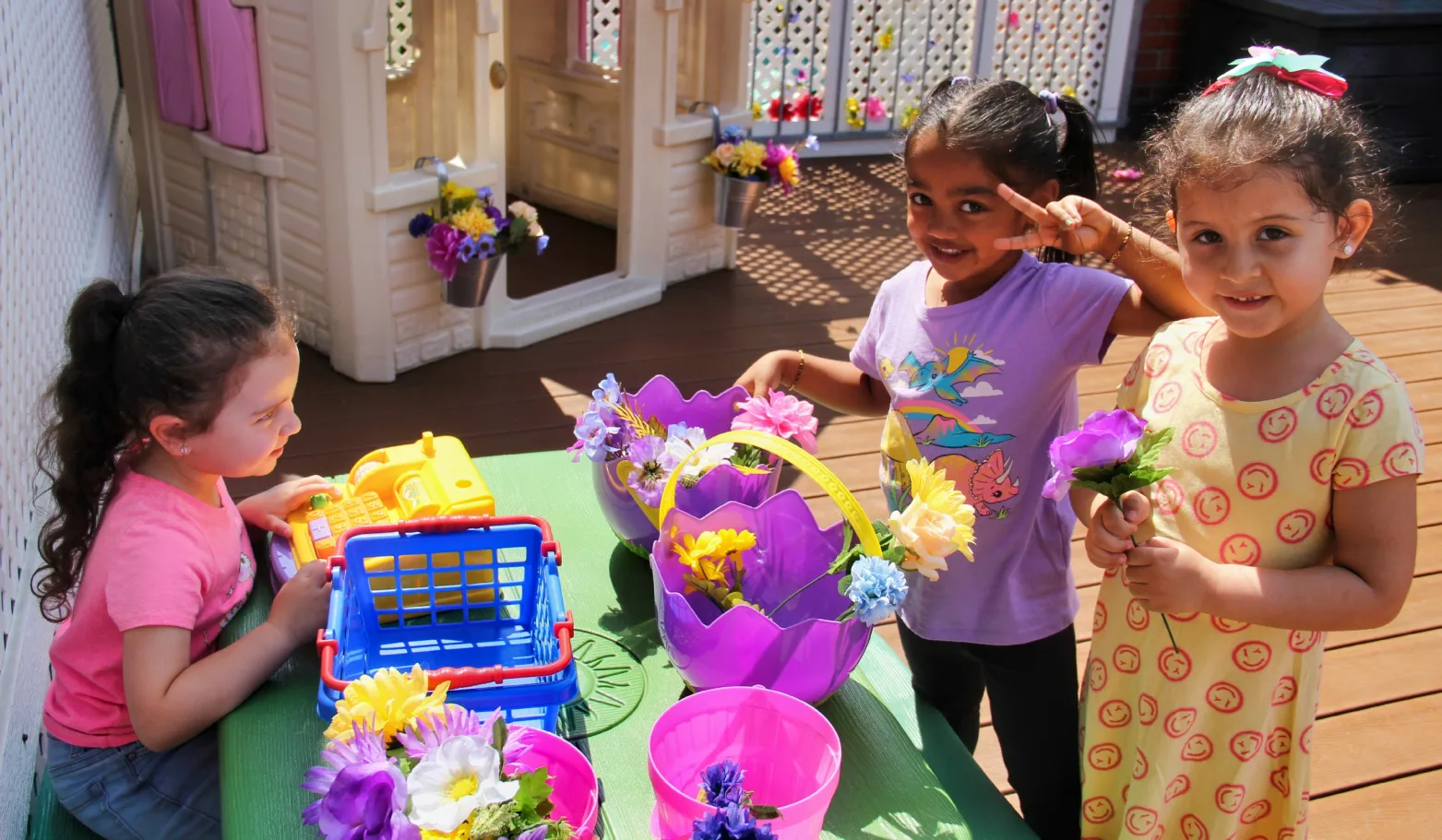 Trois enfants jouent à la boutique de fleurs avec une caisse jouet et des bouquets colorés