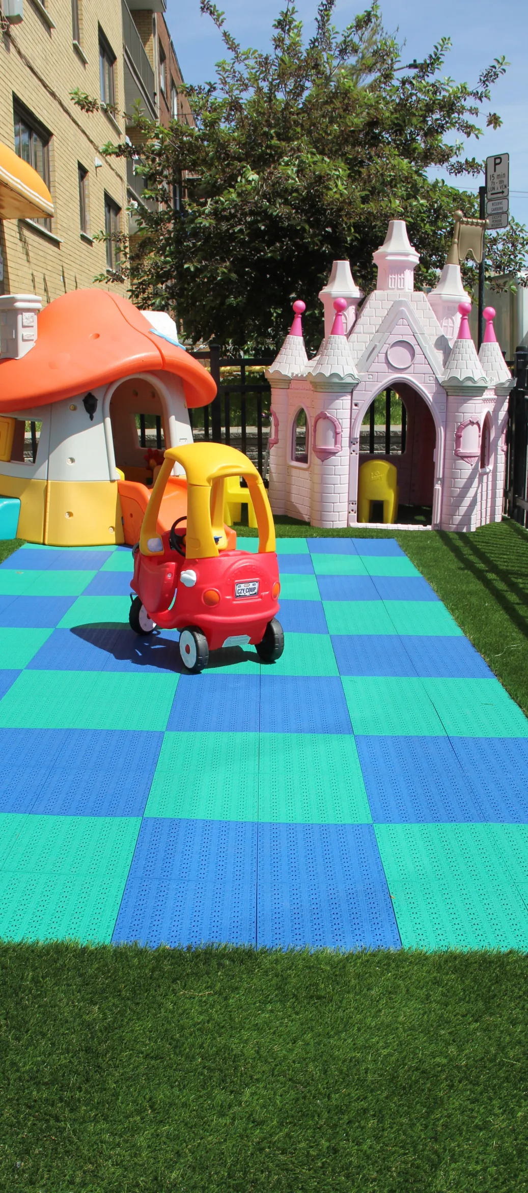 Petite auto rouge et jaune sur des tuiles de jeu bleues et vertes, près d'un château rose