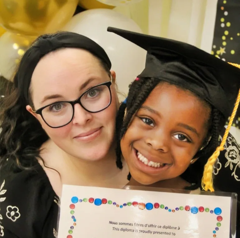 Une femme et une fillette souriante en mortier posent ensemble avec son certificat.