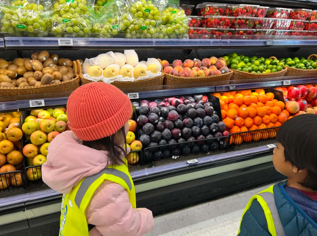 Deux enfants admirent les étalages de fruits colorés au rayon des fruits