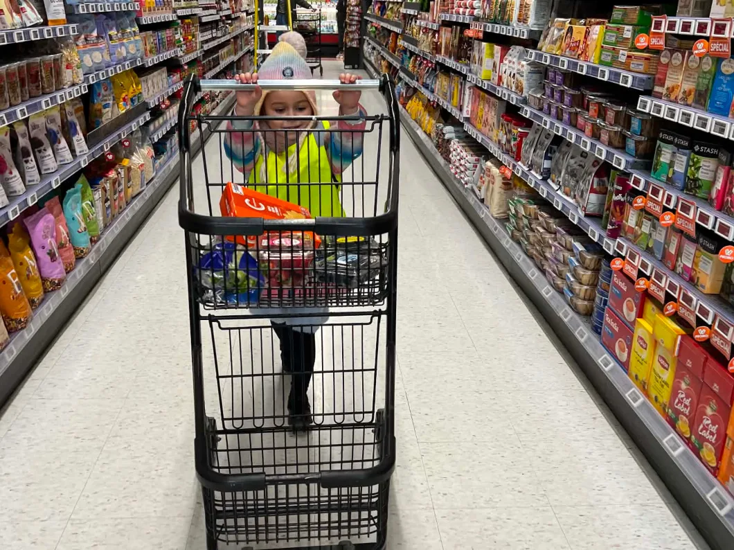Un enfant pousse un panier d'épicerie dans une allée remplie de collations