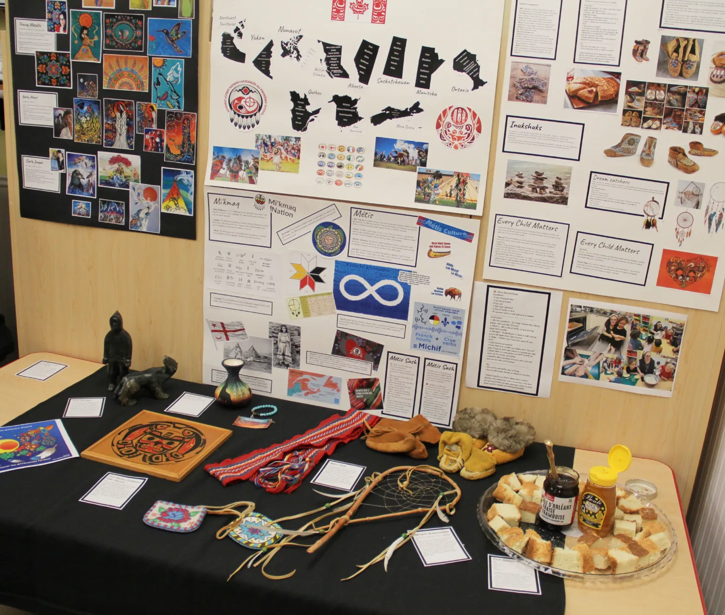 Table d'exposition d'artisanat autochtone avec mocassins et perlage, sous des affiches éducatives