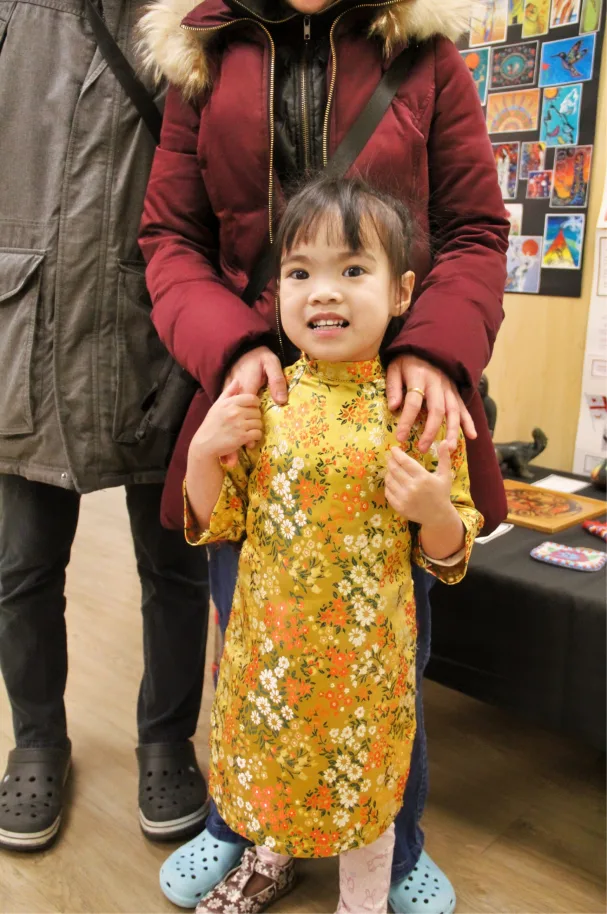 Jeune fille souriante vêtue d'une robe traditionnelle jaune à motifs floraux