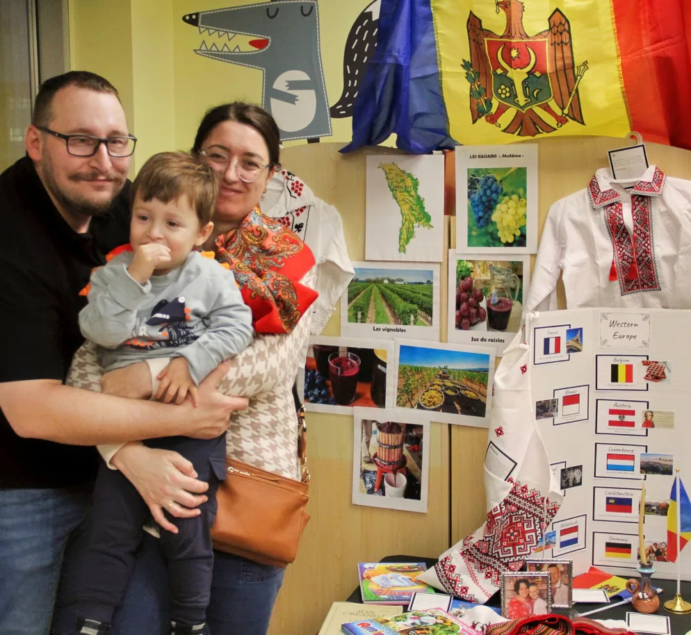 Parents avec leur bambin devant un kiosque sur la Moldavie, avec drapeaux et broderies