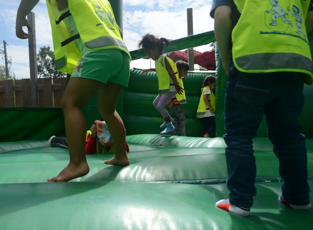 Enfants en dossards qui sautent sur un jeu gonflable vert