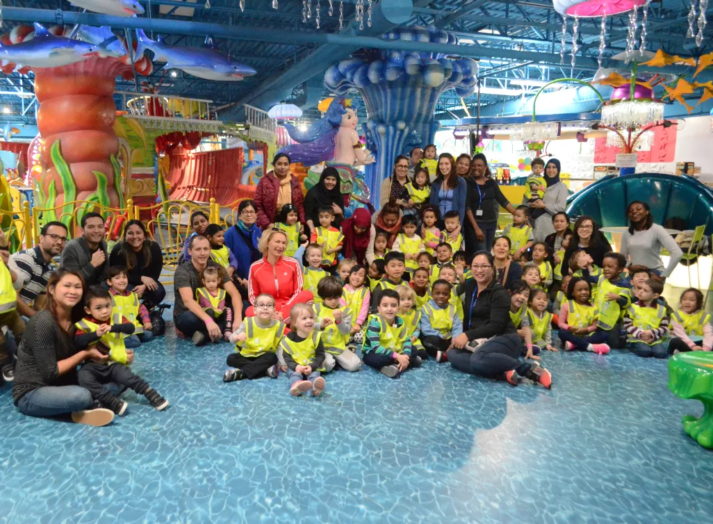 Photo de groupe des enfants et des éducatrices dans un parc d'attractions intérieur au décor marin