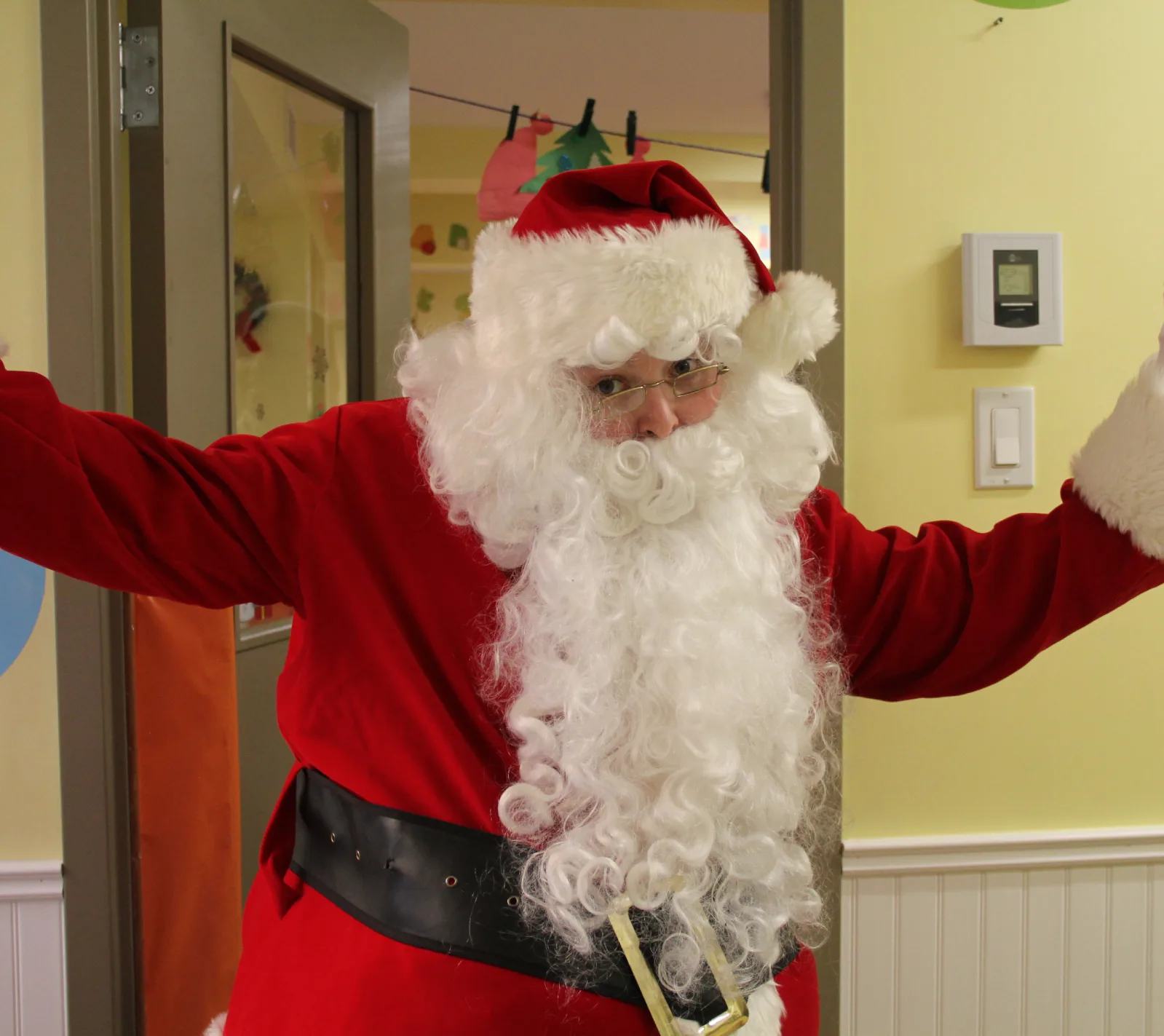 Le père Noël arrive les bras grands ouverts dans le corridor de la garderie