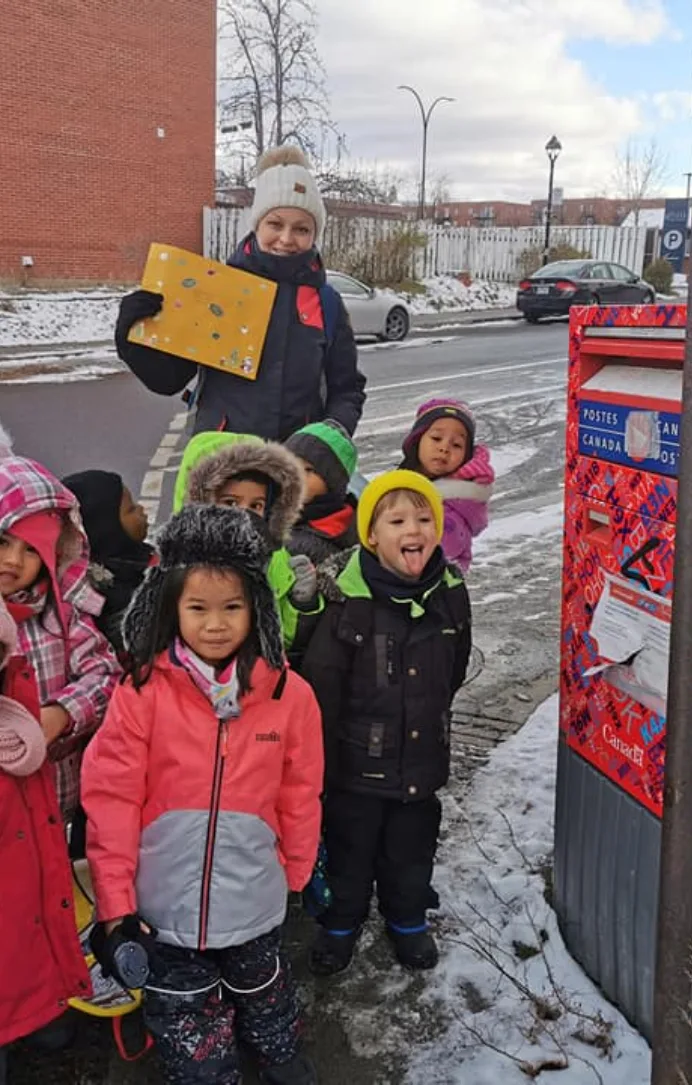Des enfants emmitouflés se rassemblent autour d'une boîte aux lettres de Postes Canada pour poster leur lettre au père Noël