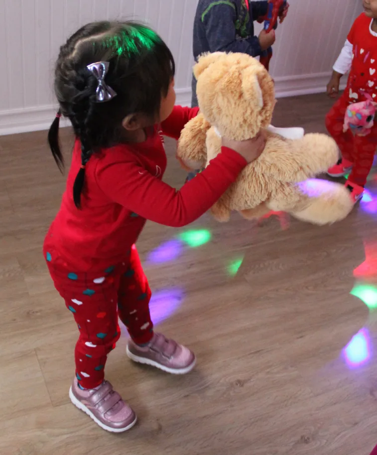Petite fille en rouge qui danse avec son toutou sous des lumières multicolores