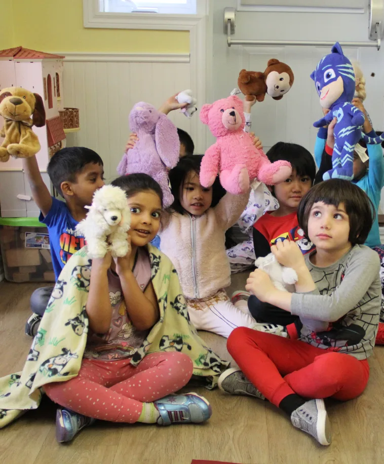 Enfants assis par terre qui montrent fièrement leurs toutous pendant le pique-nique