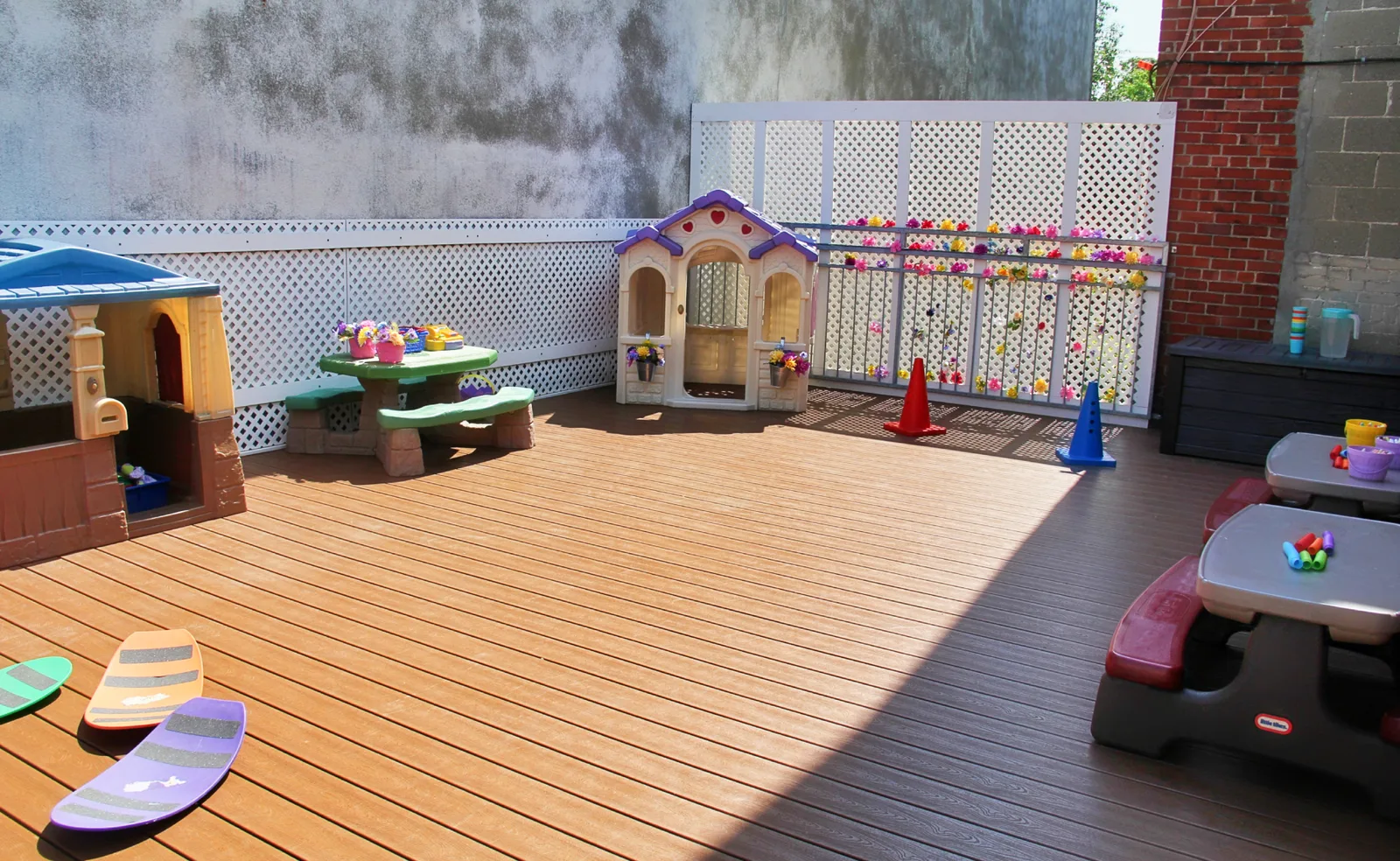 Terrasse ensoleillée sur le toit avec maisonnette, tables à pique-nique et jouets prêts pour jouer