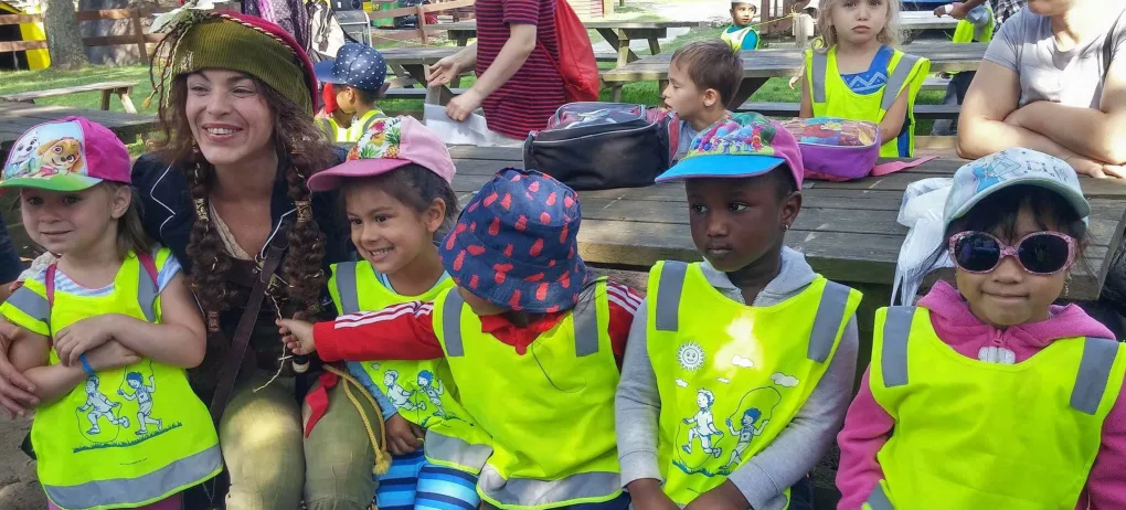 Un groupe d'enfants en dossards jaunes pose avec une animatrice costumée
