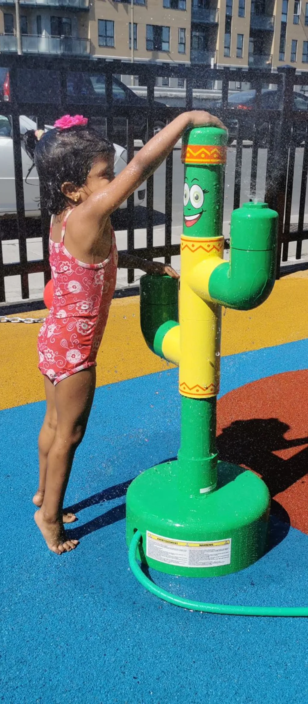 Fillette en maillot qui s'amuse avec le cactus arrosoir souriant dans les jeux d'eau