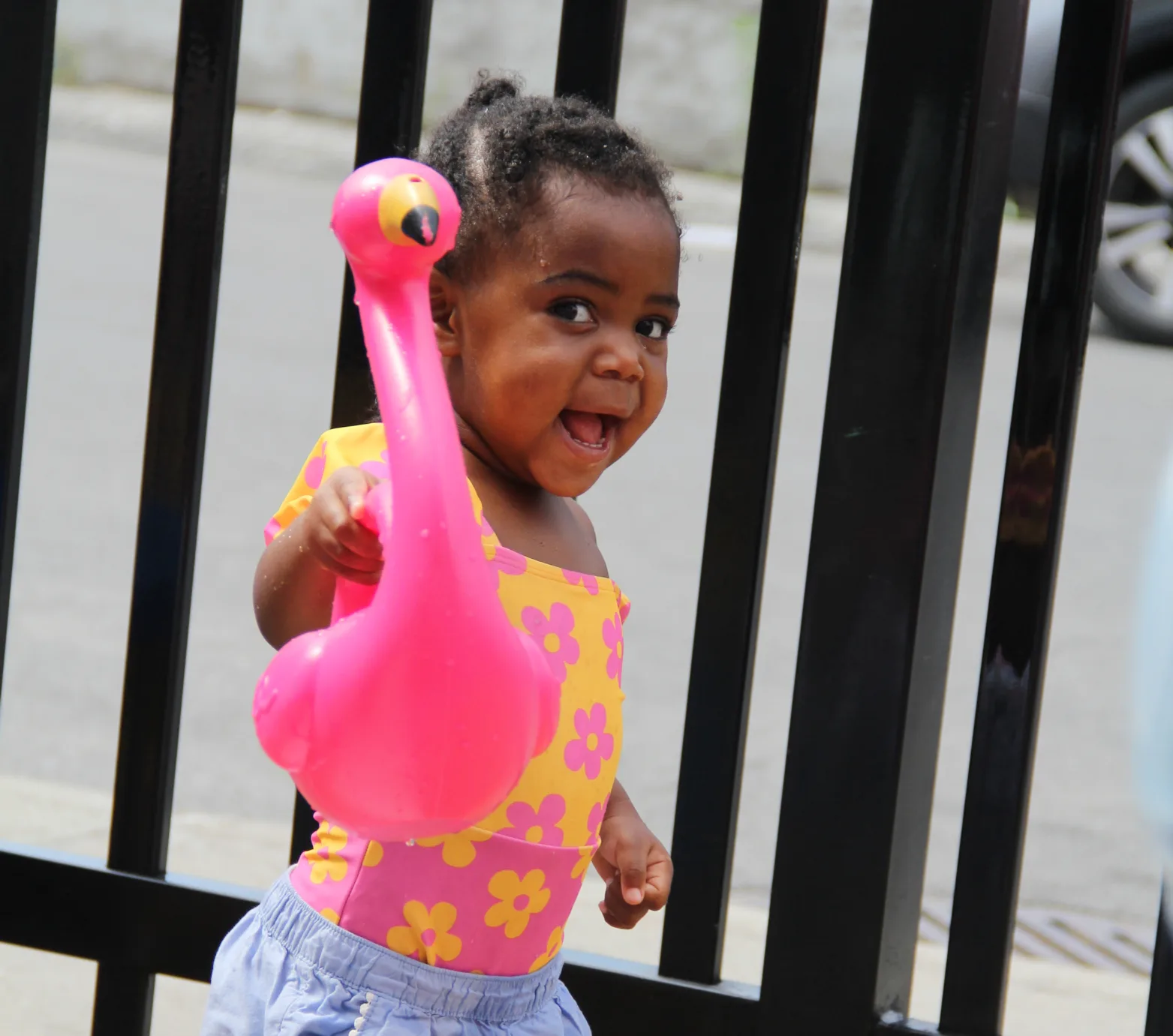 Tout-petit tout sourire avec son flamant rose gonflable près de la clôture